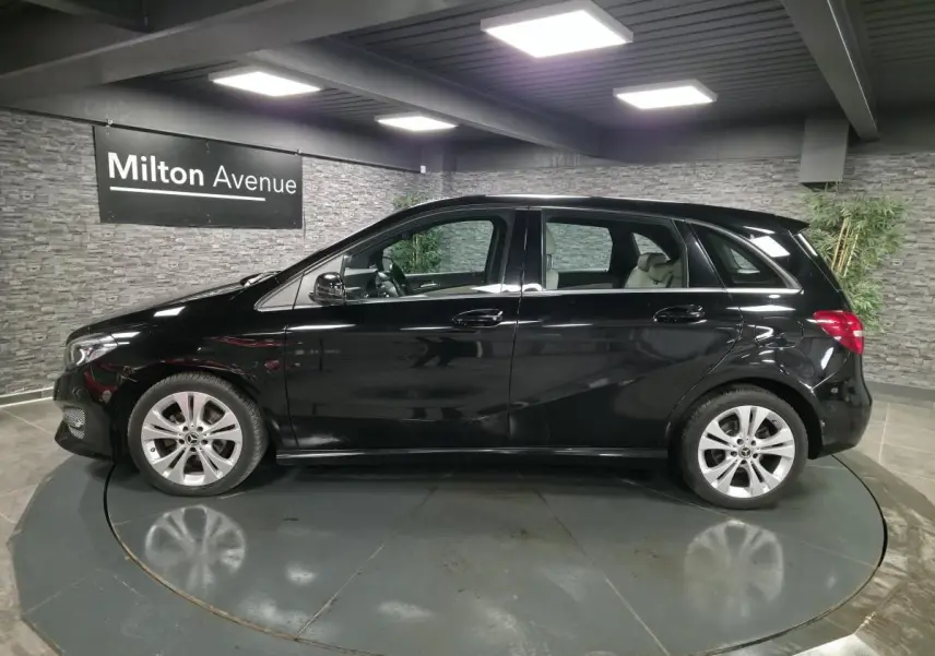 Vue de profil côté gauche d'une Mercedes Classe B noire avec jantes alliage 17 pouces dans un showroom.