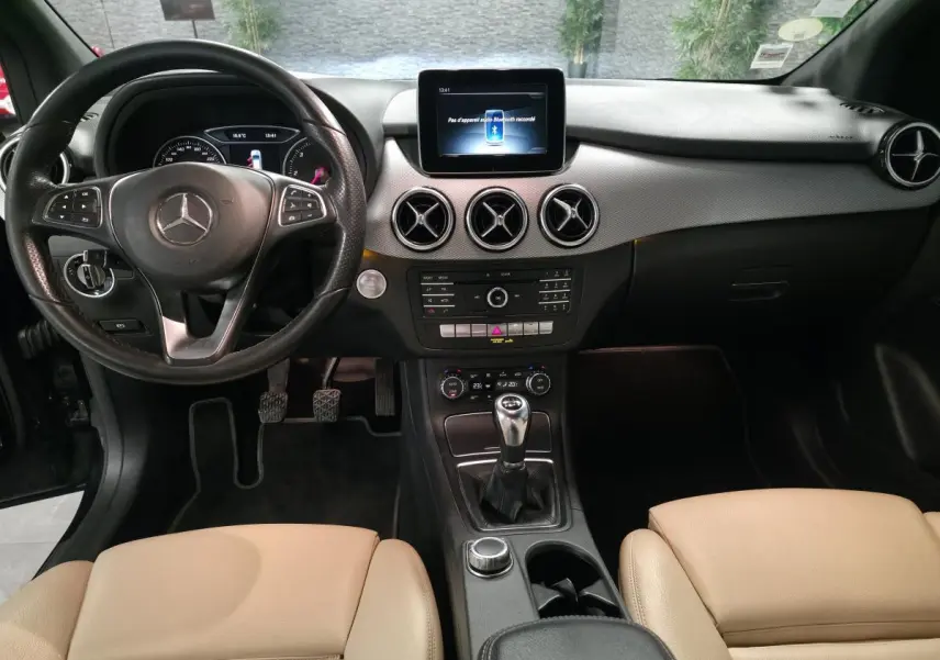Vue intérieure avant de la Mercedes Classe B 180 d Intuition 2018, volant cuir, console centrale avec boîte manuelle et écran multimédia.