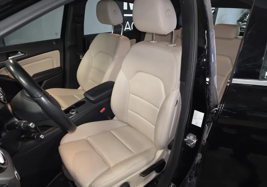 Vue intérieure côté conducteur de la Mercedes Classe B 180 d Intuition noire avec sièges avant en similicuir beige.