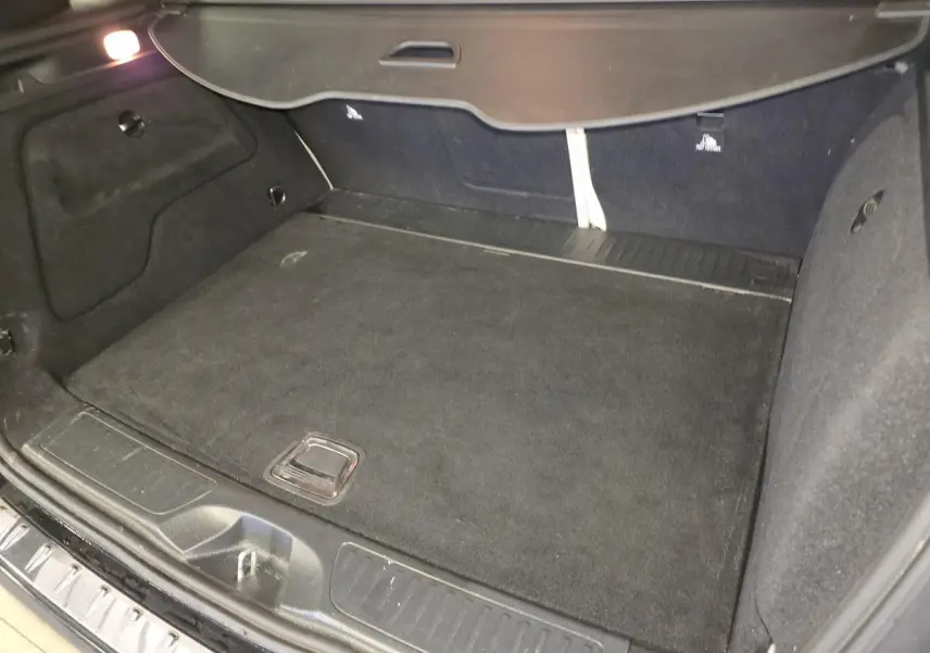 Coffre ouvert de la Mercedes Classe B 180 d Intuition noir, montrant un espace de chargement propre et tapis noir.