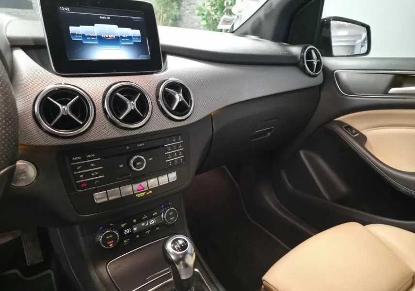 Intérieur avant droit de la Mercedes Classe B 180 d noir, tableau de bord avec écran central et levier de vitesses manuel.