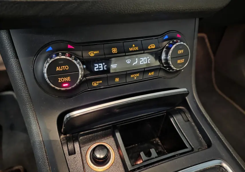 Gros plan sur la console centrale noire de la Mercedes Classe B 180 d 2018 avec commandes de climatisation et rangement ouvert.