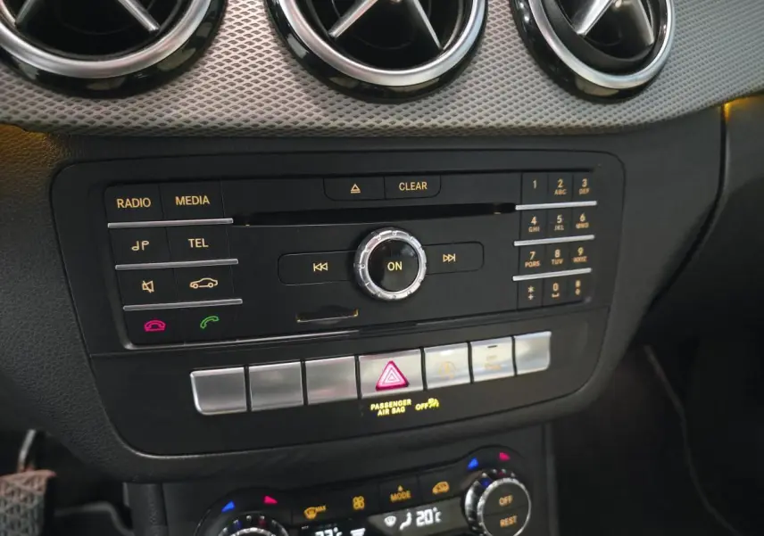 Vue rapprochée de la console centrale noire de la Mercedes Classe B 180 d Intuition avec commandes multimédia et climatisation digitale.