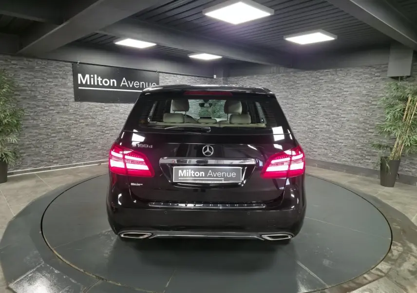 Vue arrière d'une Mercedes Classe B 180 d Intuition noire, feux LED allumés, double sortie d'échappement visible.