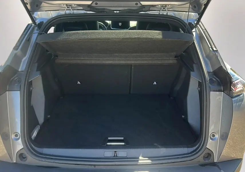 Coffre ouvert vu de l’arrière d’un Peugeot 2008 gris Artense, avec cache-bagages relevé et intérieur spacieux.