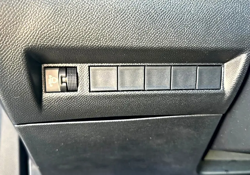 Gros plan sur les commandes de réglage des phares et emplacements vides sur le tableau de bord noir d'une Peugeot 2008 gris artense.