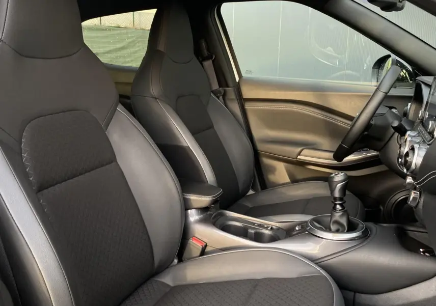 Intérieur du Nissan Juke N-Connecta 2024, vue côté conducteur, sellerie mixte noire avec volant et levier de vitesse manuels.