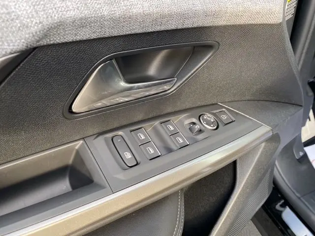 Gros plan sur la porte avant gauche du Peugeot 5008 noir Perla Nera, montrant les commandes des vitres et le bouton de réglage des rétroviseurs.