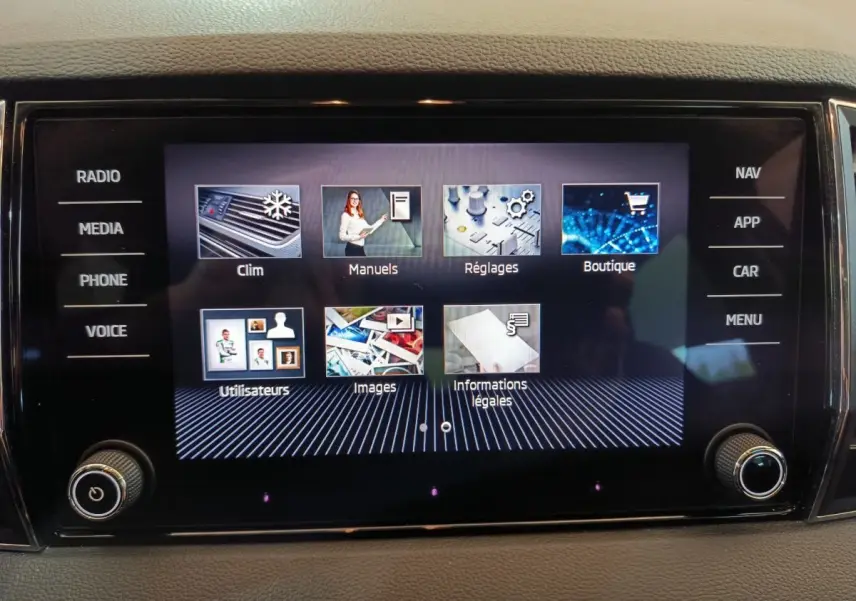 Écran tactile central du Skoda Karoq blanc 2024 affichant le menu principal avec options clim, réglages et navigation.