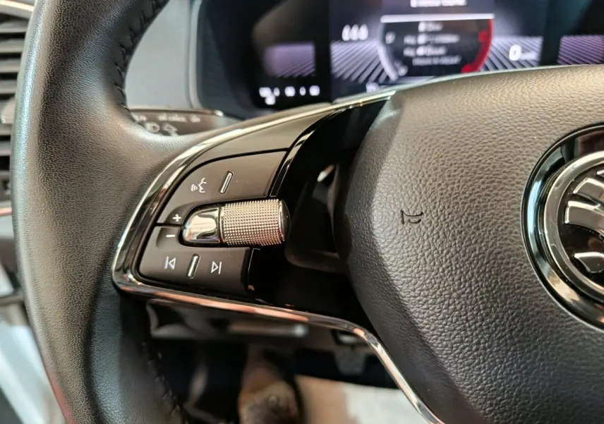 Gros plan sur le volant cuir noir du Skoda Karoq 2024, avec commandes multifonctions et molette métallique côté gauche.