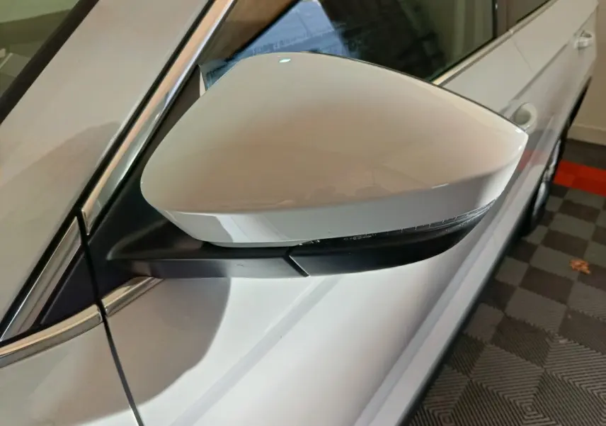 Rétroviseur droit blanc du Skoda Karoq 2024, vue rapprochée montrant le clignotant intégré et la carrosserie blanche.