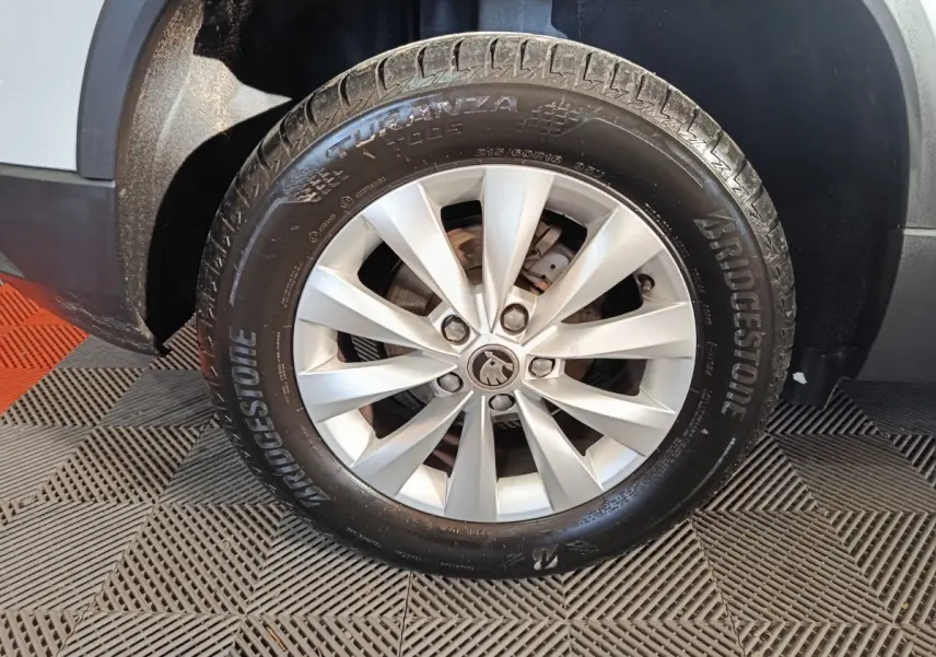 Gros plan sur la roue avant droite d’un Skoda Karoq blanc avec jante alliage et pneu Bridgestone.
