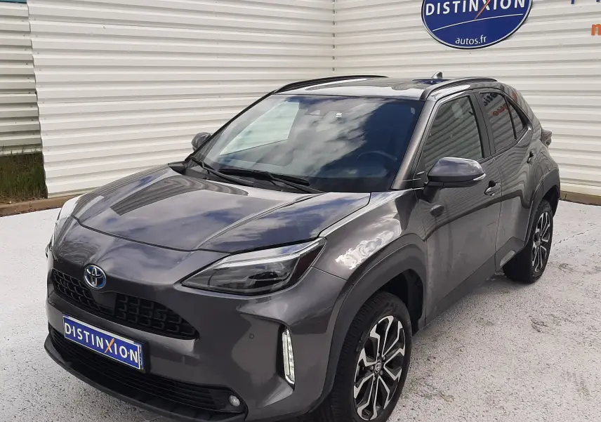 Toyota Yaris Cross gris atlas métal vue 3/4 avant droit, avec jantes alliage bicolores et toit noir brillant.