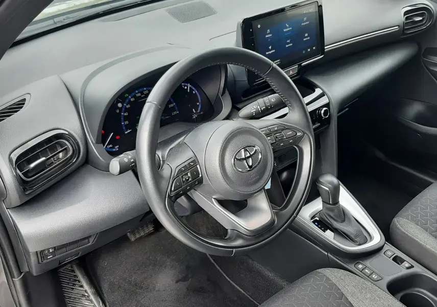Vue intérieure côté conducteur de la Toyota Yaris Cross 2024, tableau de bord gris avec écran tactile et volant multifonction.