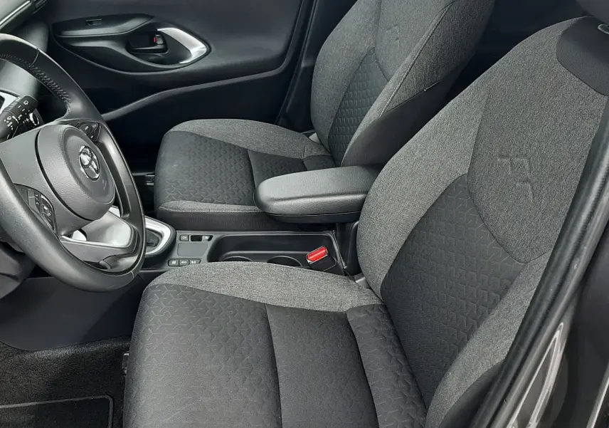 Vue intérieure côté conducteur de la Toyota Yaris Cross 2024, sièges tissu gris bicolore avec accoudoir central.