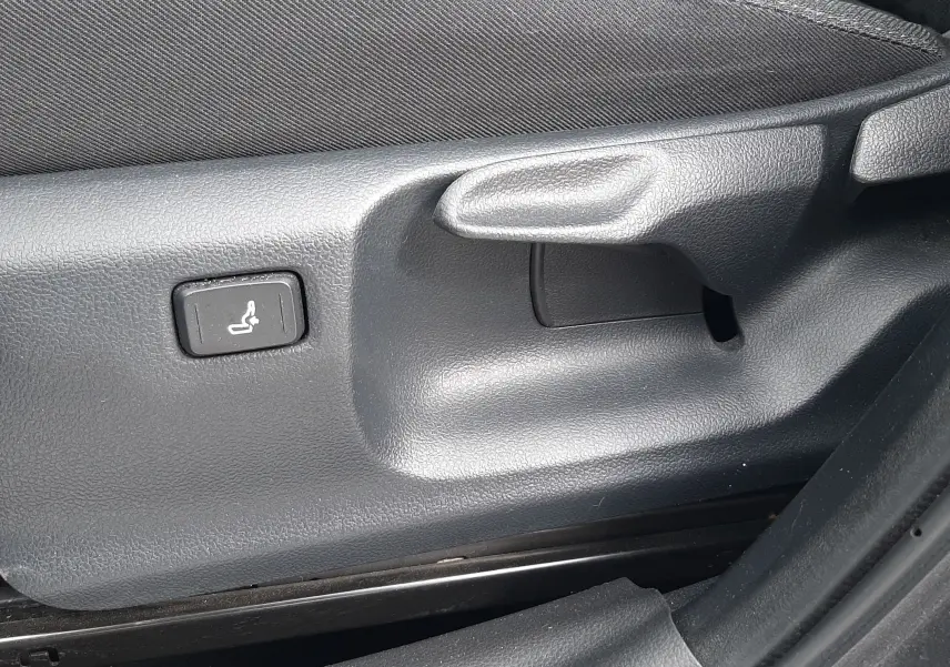Détail du réglage manuel et bouton de siège chauffant sur le côté gauche d’un siège tissu gris dans une Toyota Yaris Cross 2024.