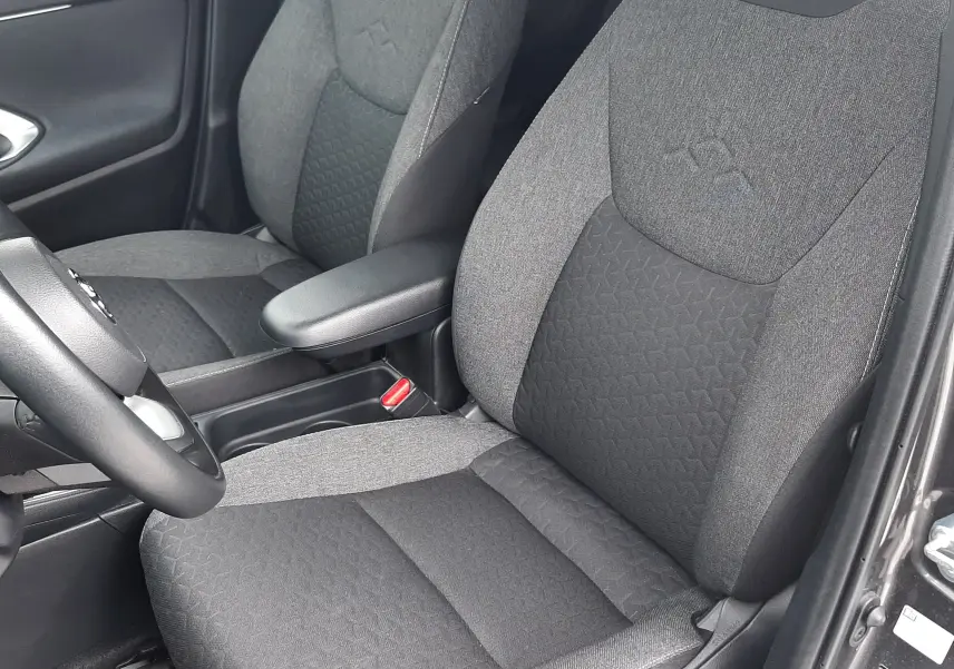 Vue intérieure rapprochée des sièges avant en tissu gris foncé et clair de la Toyota Yaris Cross 2024 hybride.
