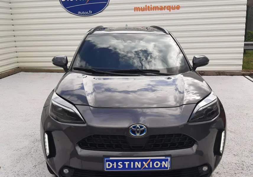 Vue de face de la Toyota Yaris Cross 2024 gris atlas métal, avec calandre noire et feux LED verticaux allumés.