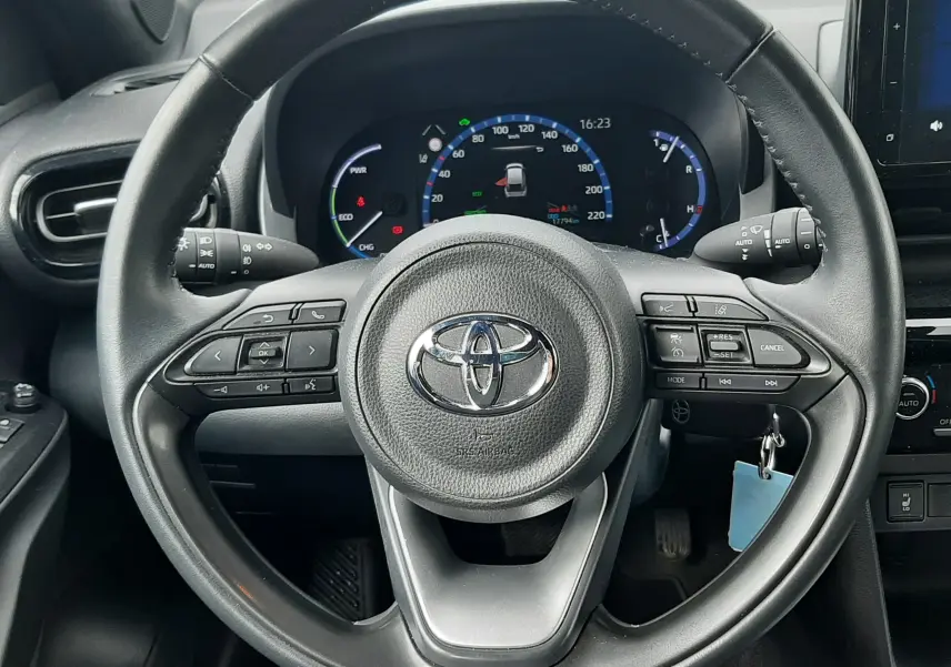 Vue intérieure centrée sur le volant noir de la Toyota Yaris Cross 2024 avec tableau de bord digital et commandes au volant.