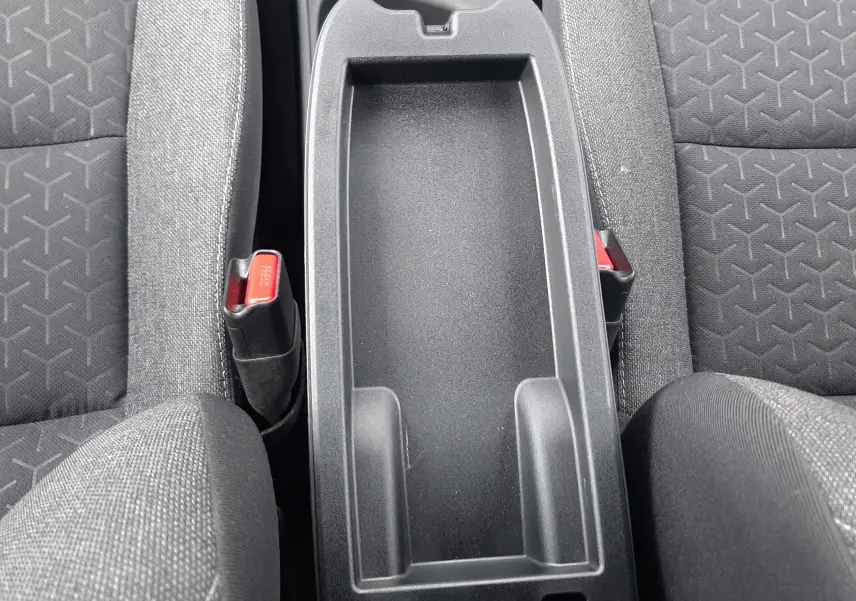 Vue plongeante sur la console centrale noire entre les sièges tissu gris foncé de la Toyota Yaris Cross 2024.