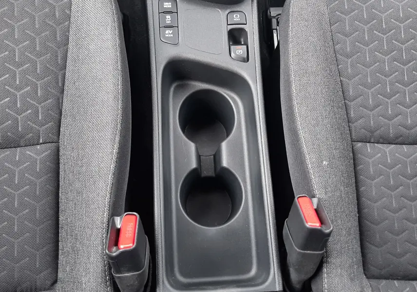 Vue plongeante sur la console centrale noire et les sièges tissu gris foncé du Toyota Yaris Cross 2024 hybride.