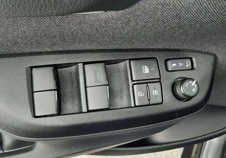 Gros plan sur les commandes de lève-vitres et réglage des rétroviseurs côté conducteur de la Toyota Yaris Cross gris atlas 2024.