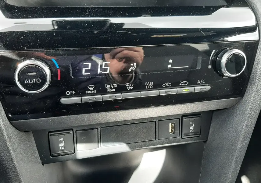 Détail de la console centrale noire de la Toyota Yaris Cross 2024, affichant la climatisation à 21,5°C et commandes tactiles.