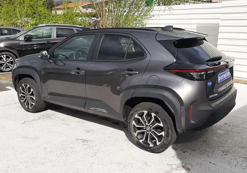 Vue 3/4 arrière droite d'une Toyota Yaris Cross 2024 gris atlas métal avec jantes bi-ton et toit noir.