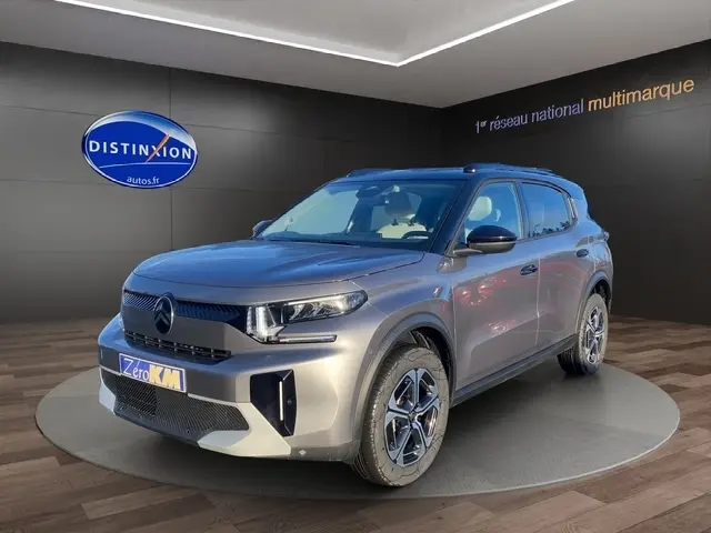 Vue 3/4 avant d'un Citroën C3 Hybrid 145 E-DCS6 MAX gris foncé avec jantes distinctives en concession.
