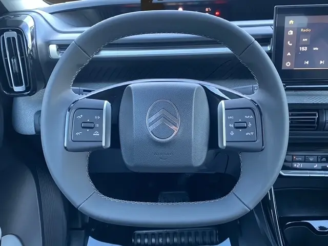 Vue rapprochée du volant en cuir synthétique gris foncé de la Citroën C3 Hybrid 145 E-DCS6 MAX avec commandes intégrées.