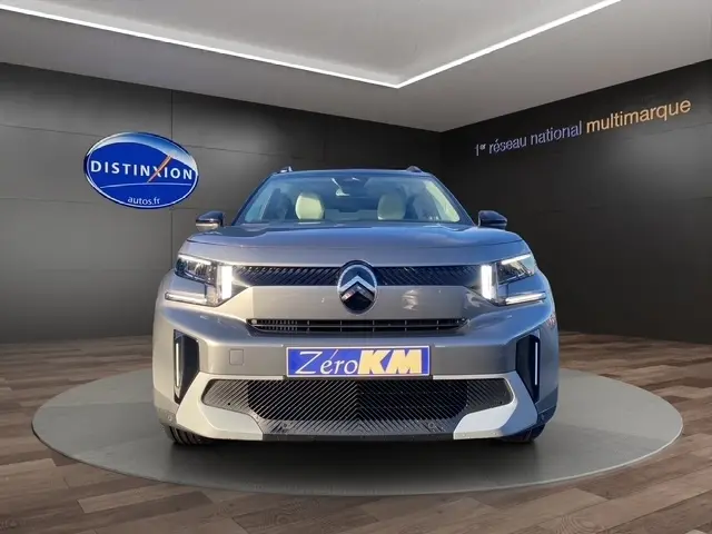 Citroën C3 Hybrid 145 gris foncé vue de face en intérieur avec logo Distinxion en arrière-plan.