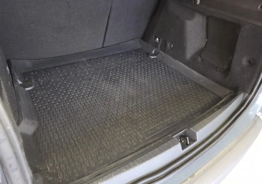 Vue rapprochée de la malle arrière grise du Dacia Duster 2024 avec tapis de coffre noir marqué Duster.