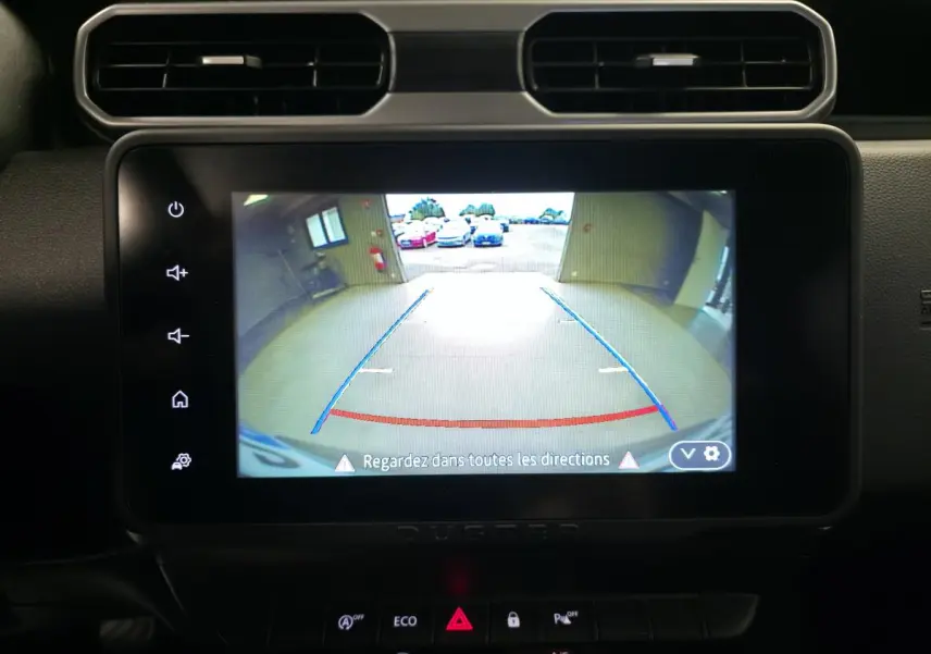 Écran tactile intérieur du Dacia Duster 2024 montrant la caméra de recul avec lignes de guidage bleues et rouges.