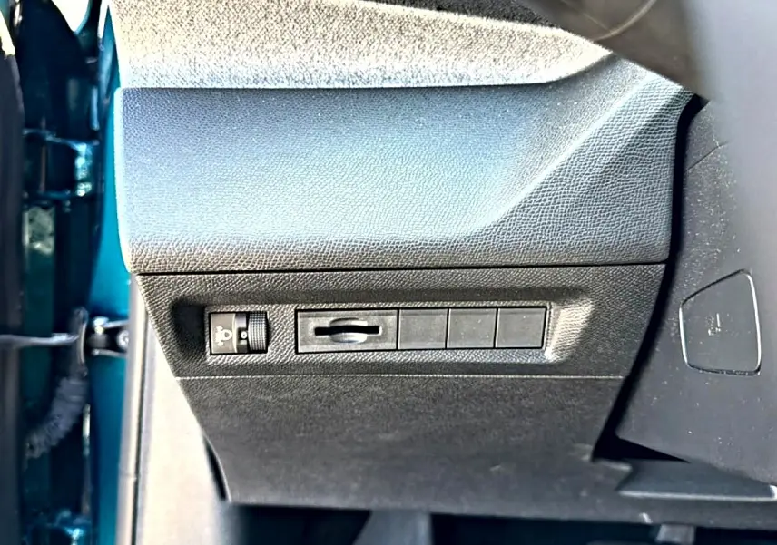 Vue rapprochée du panneau de commandes latéral gauche intérieur de la Peugeot 408 bleu, avec réglage éclairage et emplacements vides.