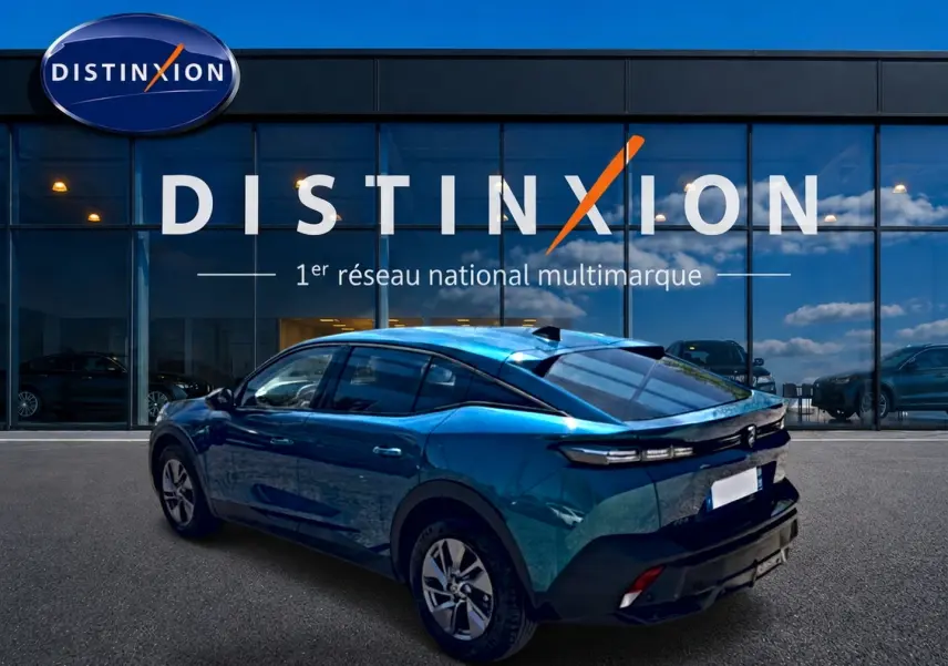 Vue 3/4 arrière droite d'une Peugeot 408 Hybrid 145 allure e-dcs6 bleu devant une vitrine Distinxion.