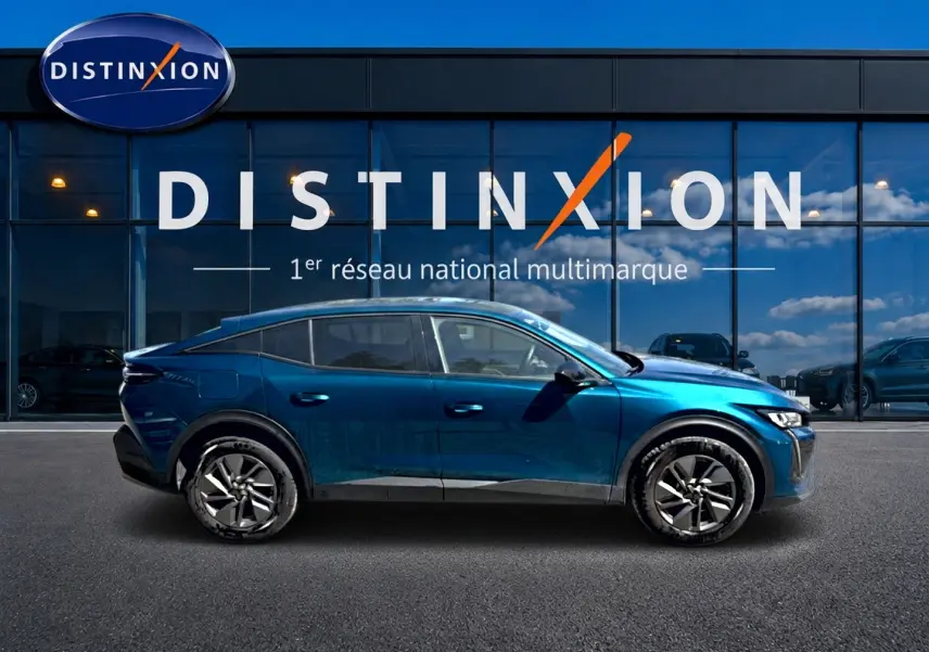Vue latérale droite d'une Peugeot 408 Hybrid 145 allure e-dcs6 bleu avec jantes alu, devant une vitrine Distinxion.