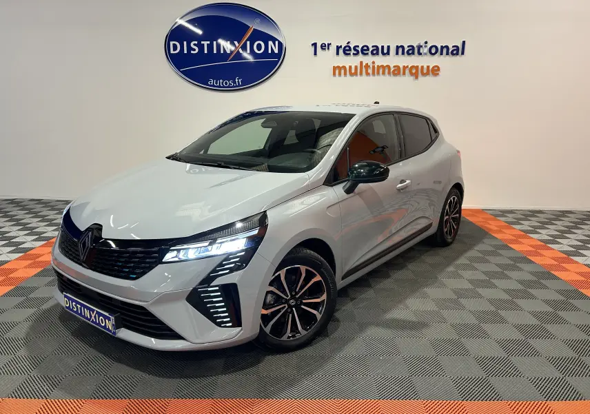 Renault Clio V E-Tech gris Rafale vue 3/4 avant droit avec phares LED allumés en showroom.