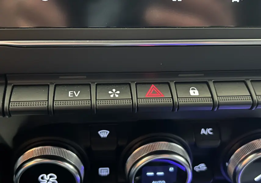 Gros plan sur la console centrale de la Renault Clio V hybride, montrant les boutons de contrôle et les molettes argentées.