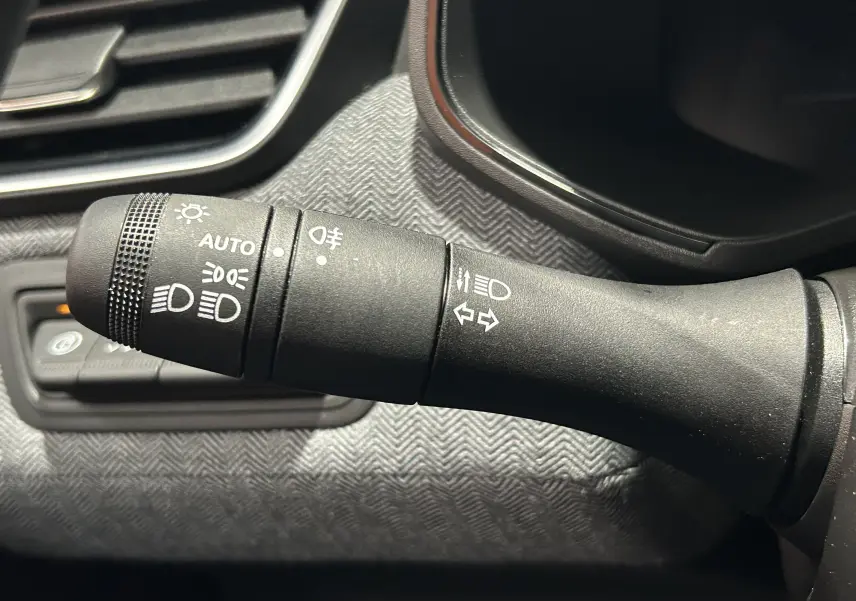 Gros plan sur la commande des feux et clignotants dans l’habitacle gris noir de la Renault Clio V E-Tech Hybrid.