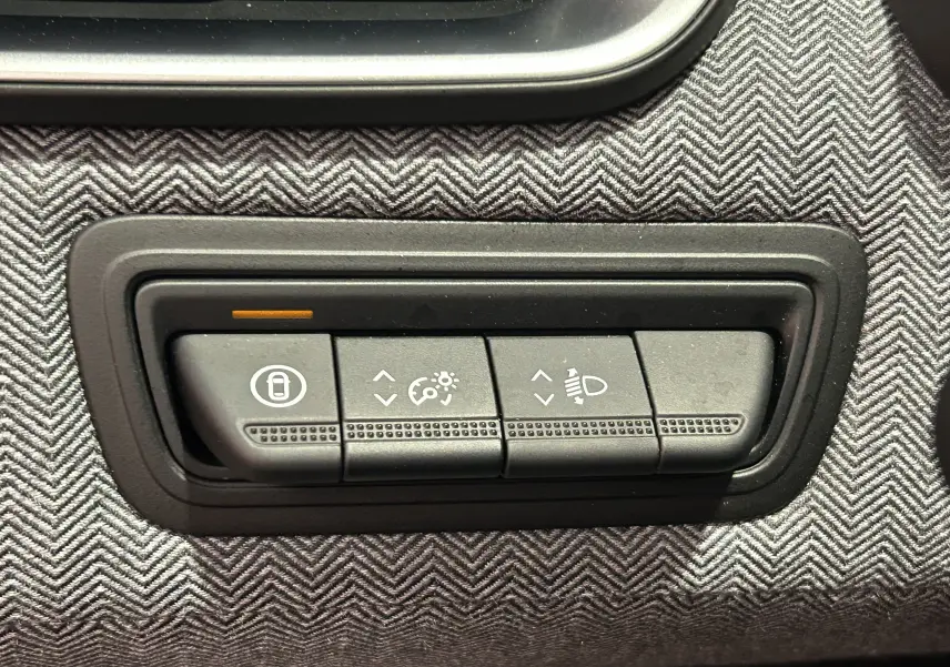 Gros plan sur les boutons de réglage d’éclairage et verrouillage dans l’habitacle gris à motif chevrons d’une Renault Clio V.