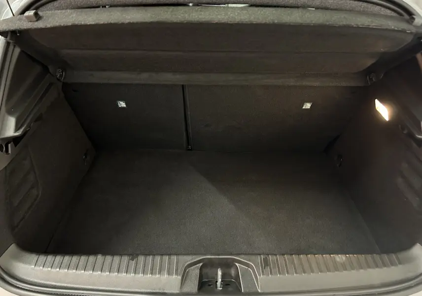 Vue intérieure du coffre spacieux et propre de la Renault Clio V E-Tech Full Hybrid 145 Gris Rafale, éclairage latéral allumé.