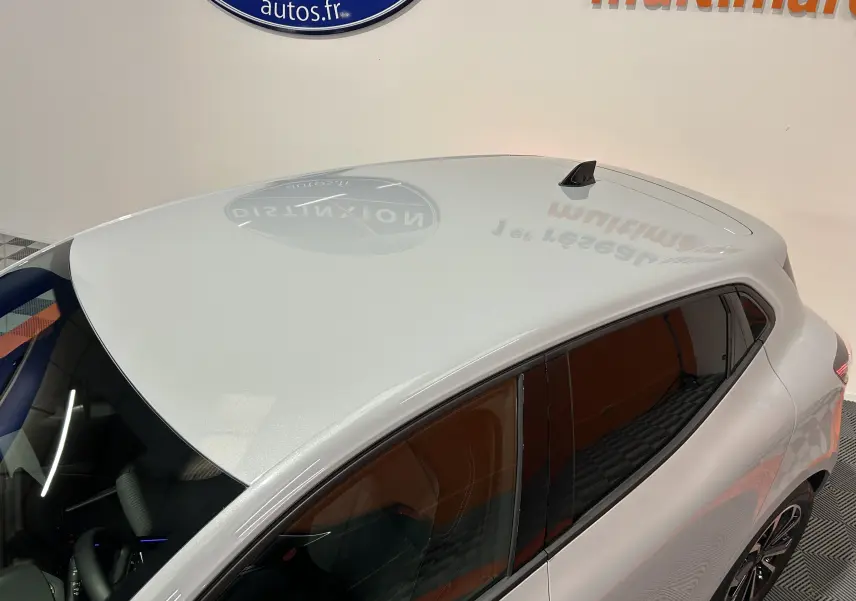 Vue plongeante sur le toit gris rafale et le côté gauche vitré d'une Renault Clio V hybride en intérieur showroom.