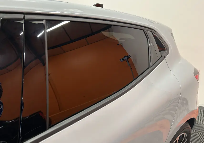 Détail du côté gauche arrière de la Renault Clio V gris Rafale avec vitres teintées et jante visible.