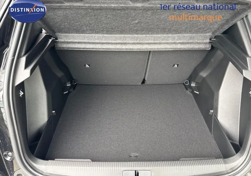 Coffre ouvert du Peugeot 2008 Hybrid noir métal, montrant l'espace de chargement vide et la finition intérieure sombre.