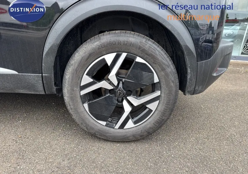 Gros plan sur la roue avant gauche du Peugeot 2008 noir métal avec jante alliage bicolore distinctive.