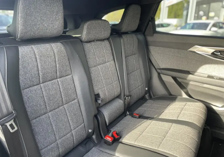 Vue latérale intérieure montrant la banquette arrière en tissu gris avec surpiqûres blanches du Renault Espace 2024.