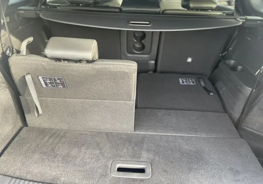 Vue intérieure du coffre du Renault Espace noir étoilé 2024, siège arrière partiellement rabattu côté gauche.