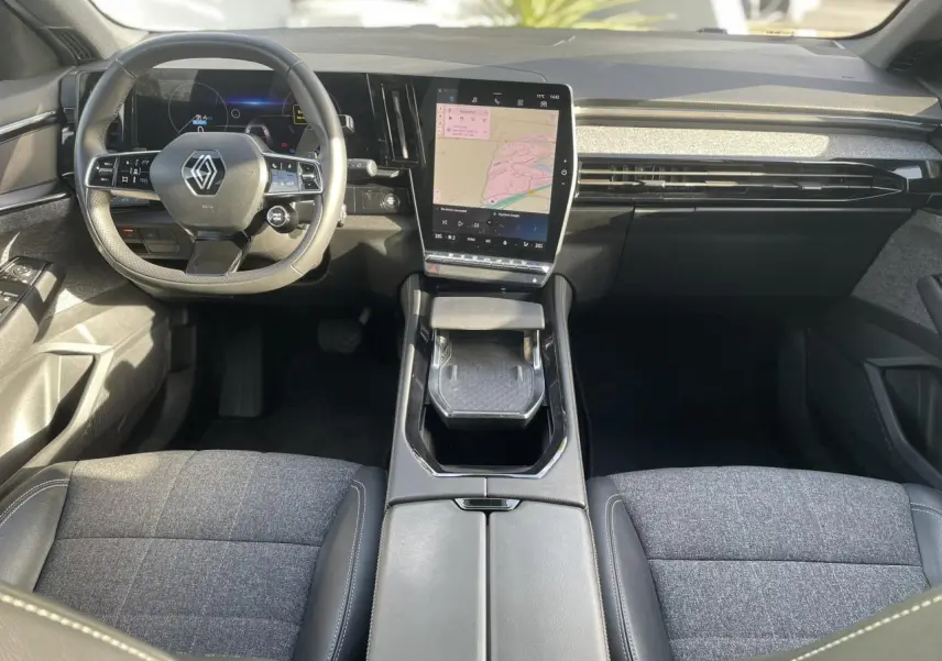 Vue intérieure avant du Renault Espace 2024, tableau de bord noir avec grand écran tactile vertical et volant multifonction.