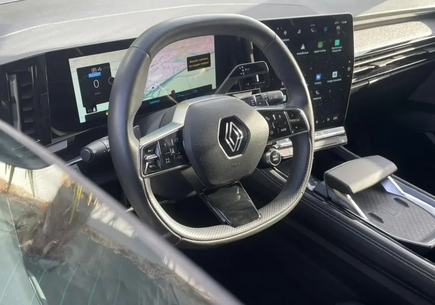 Vue intérieure du poste de conduite Renault Espace 2024, volant multifonction et grand écran tactile noir.