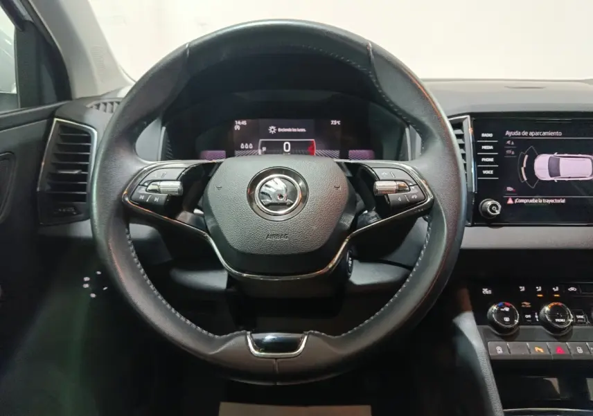 Vue intérieure centrée sur le volant cuir noir du Skoda Karoq 2024 avec tableau de bord digital et écran tactile latéral.
